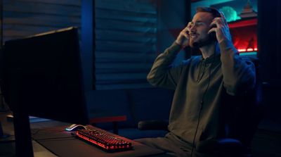 a man sitting in front of a computer talking on a cell phone