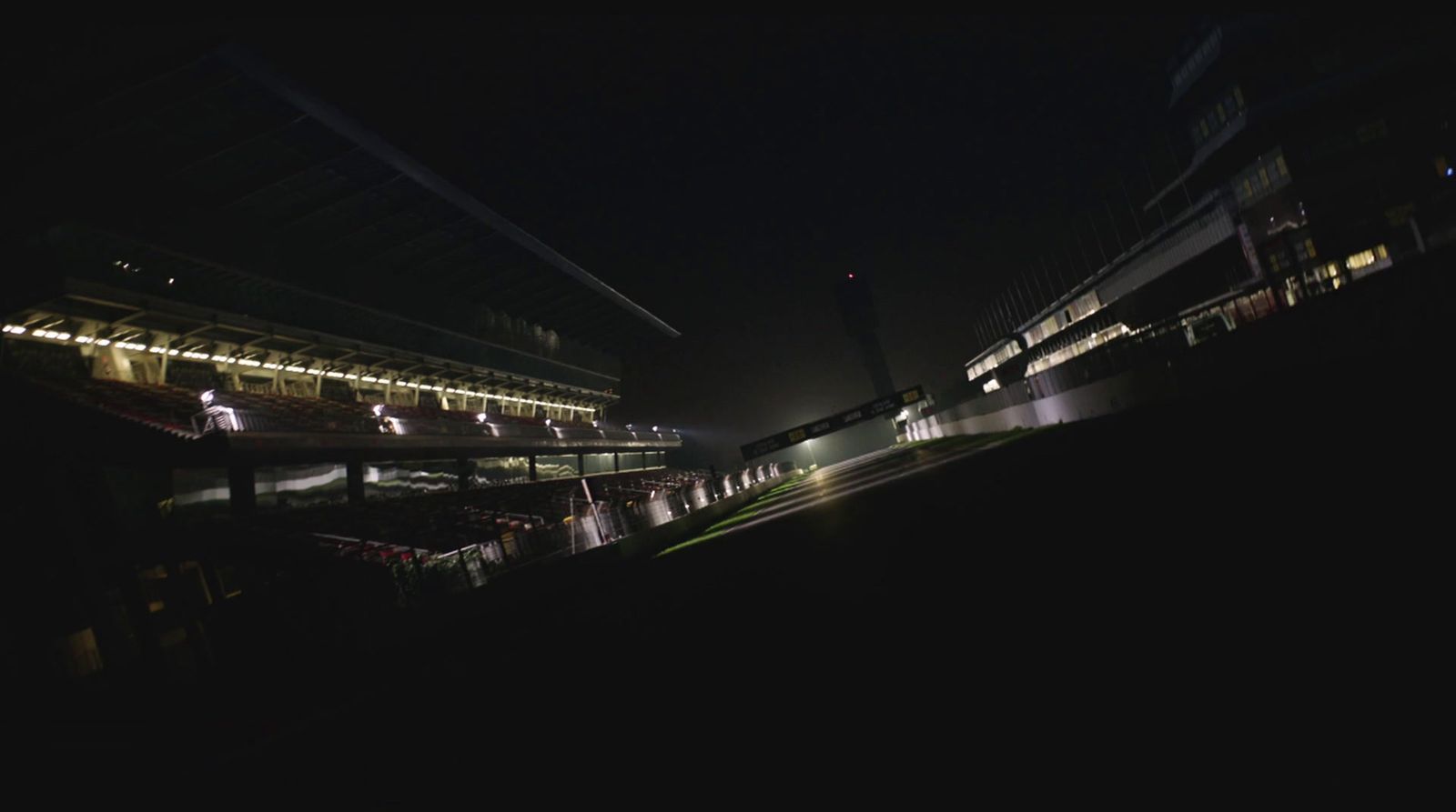 a night view of a stadium with a clock tower in the distance