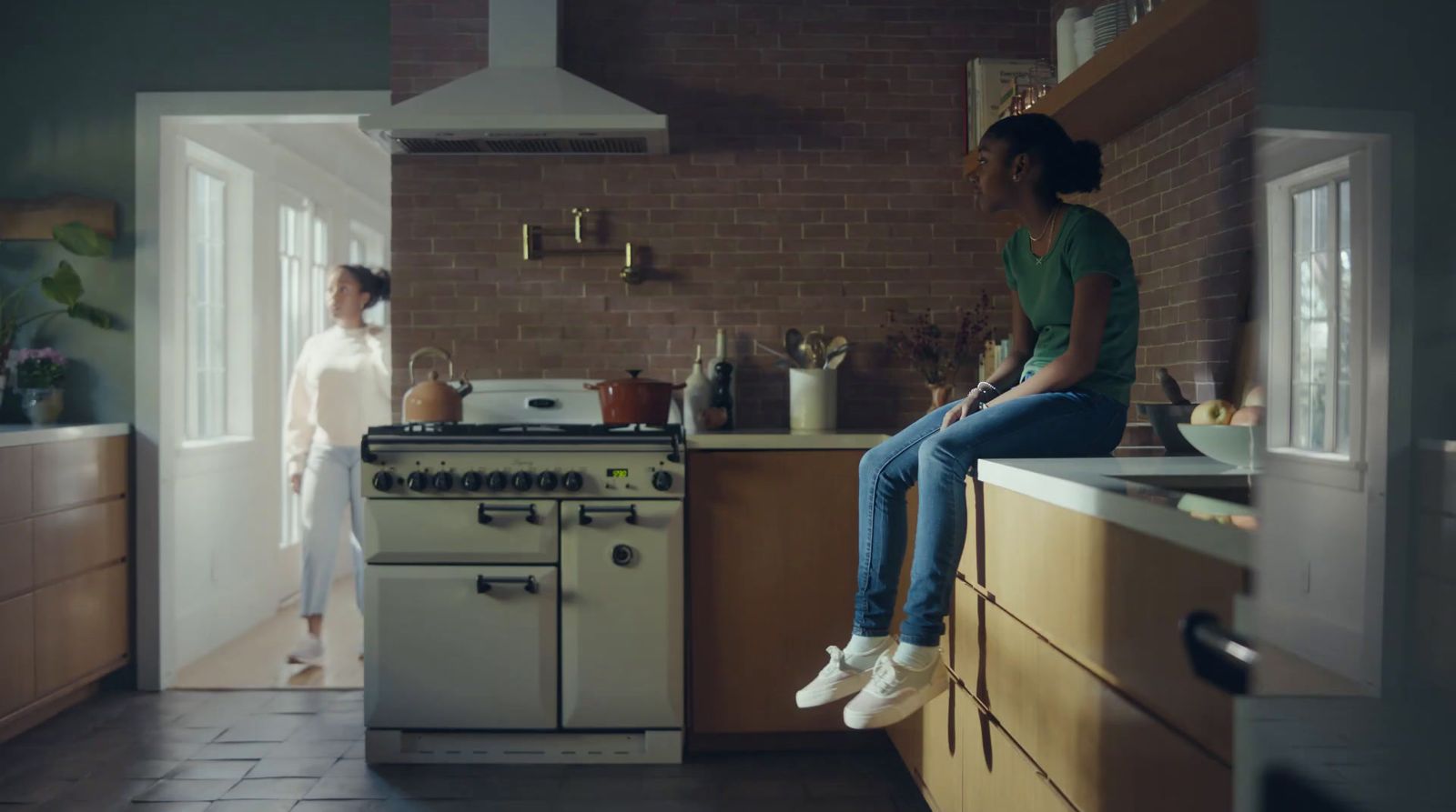 two women sitting on a counter in a kitchen