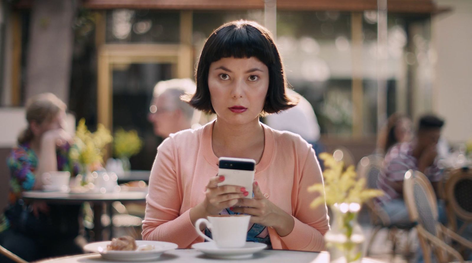 a woman sitting at a table looking at her cell phone