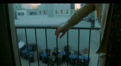 a hand reaching out of a window onto a balcony