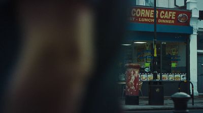 a corner cafe with a red trash can in front of it