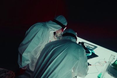 two doctors in white suits are performing surgery