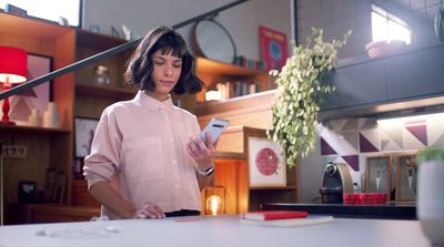 a woman standing in a kitchen looking at her cell phone