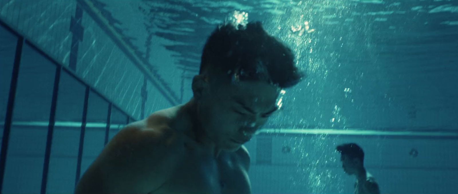 a man standing under water in a swimming pool