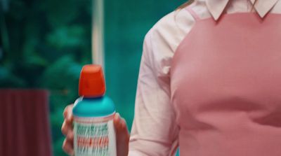 a woman in a pink dress holding a blue and orange bottle