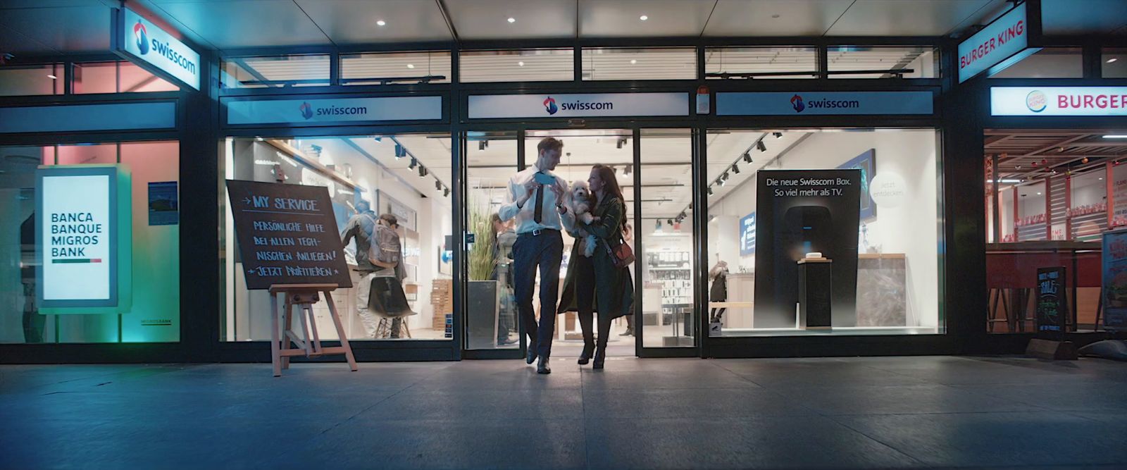 a couple of people that are walking in front of a store