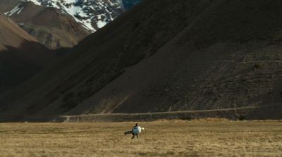 a man riding a horse through a dry grass field