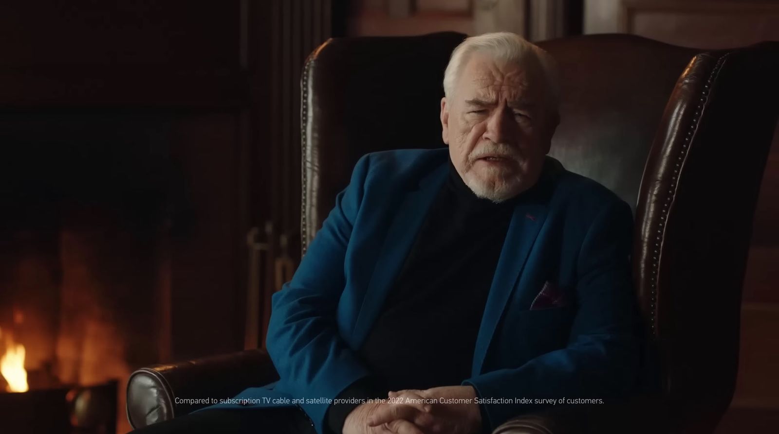 an older man sitting in a chair in front of a fireplace