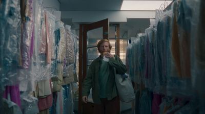 a man standing in a room filled with clothes