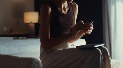 a woman sitting on a bed looking at her cell phone