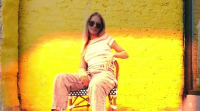 a woman sitting on a chair in front of a yellow wall