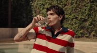 a man in a striped shirt drinking from a wine glass