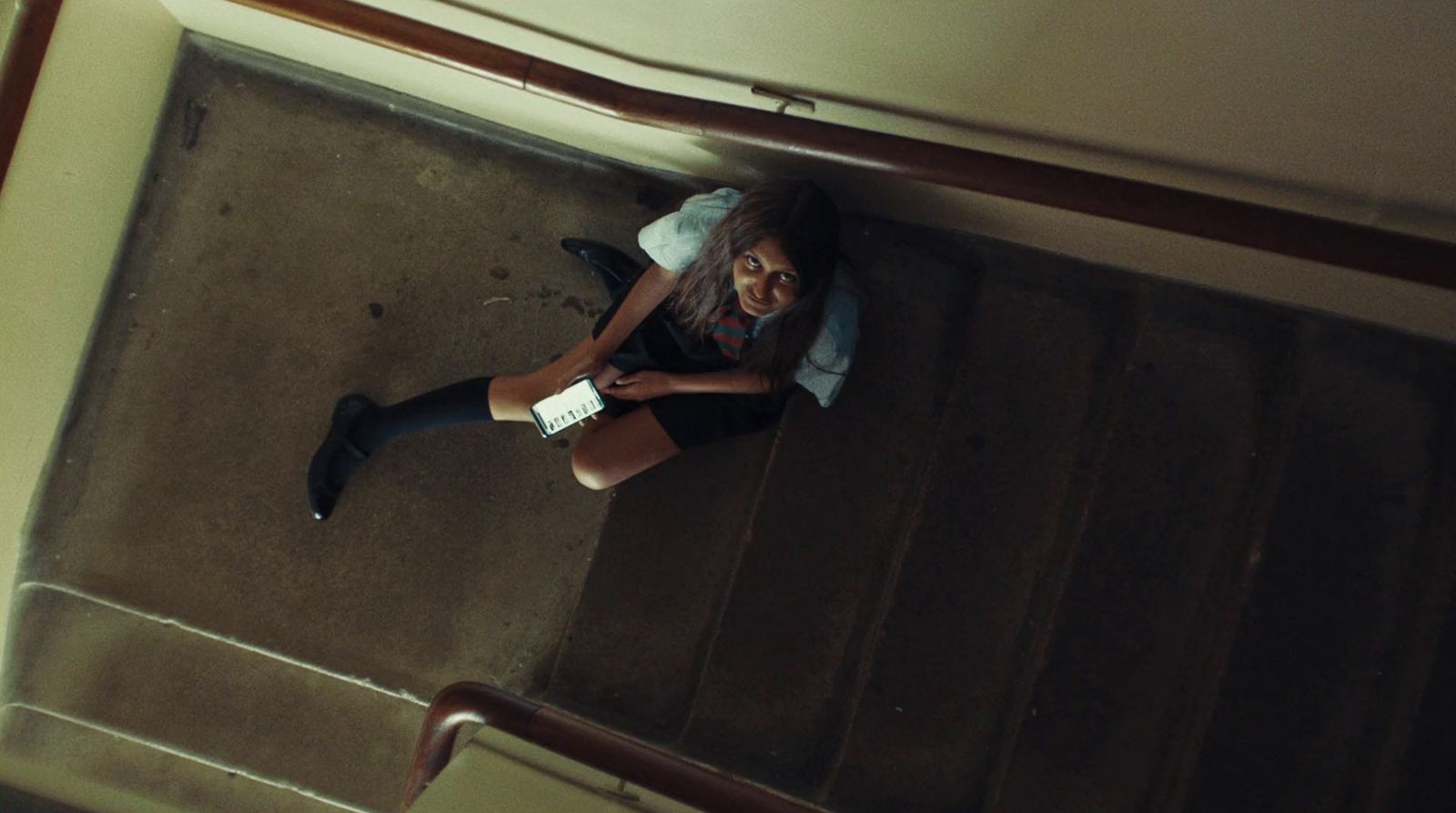 a woman sitting on the floor looking down at her cell phone