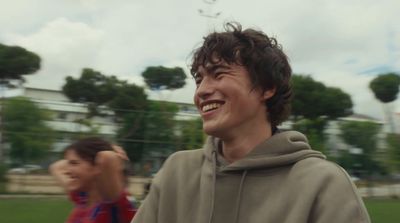 a man in a gray hoodie smiles at the camera