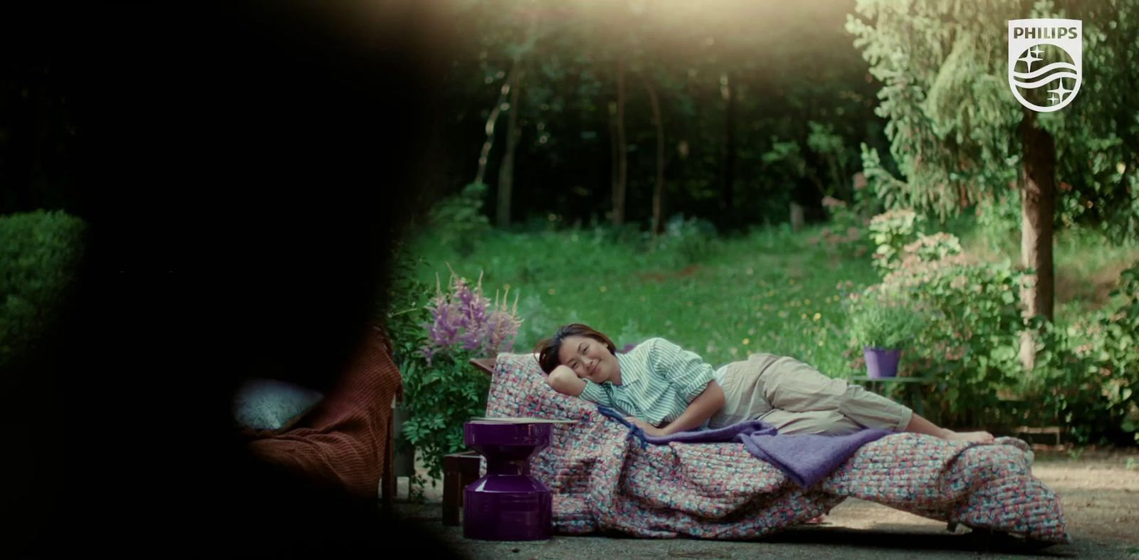 a woman laying on top of a bed next to a forest