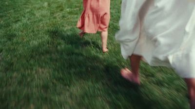 a couple of people walking across a lush green field