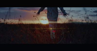 a person walking through a field at sunset