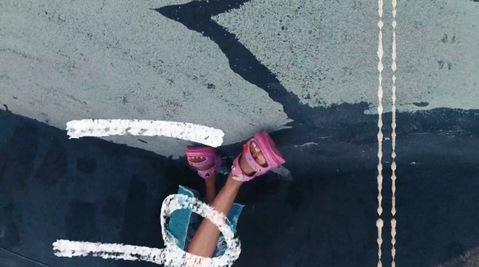 a person with pink shoes standing in the middle of a street