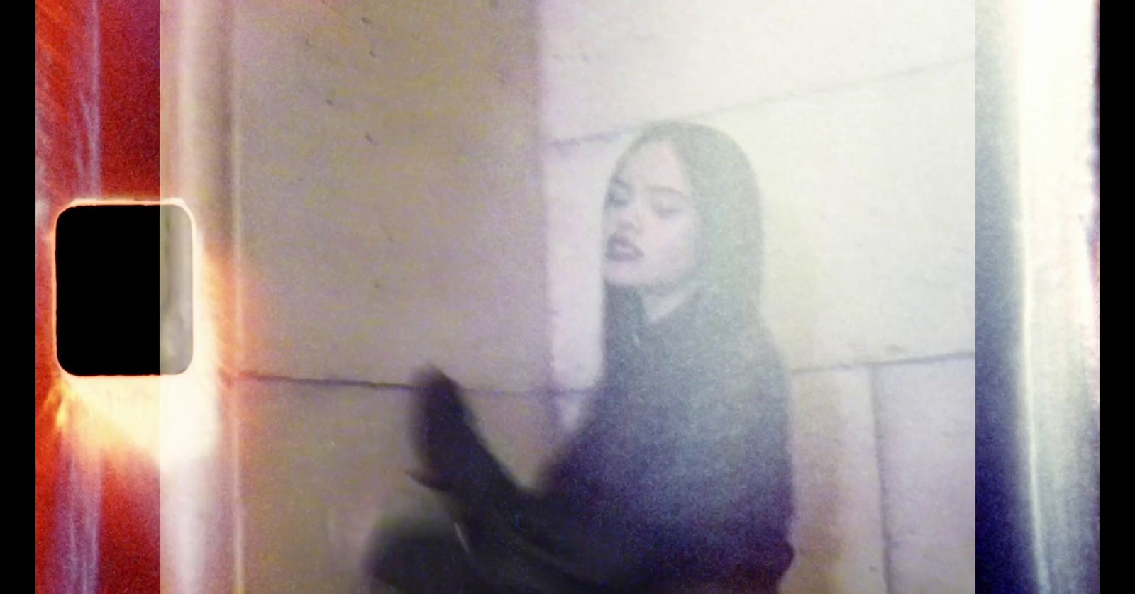 a blurry photo of a woman leaning against a wall