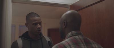 a man standing in front of a mirror looking at another man