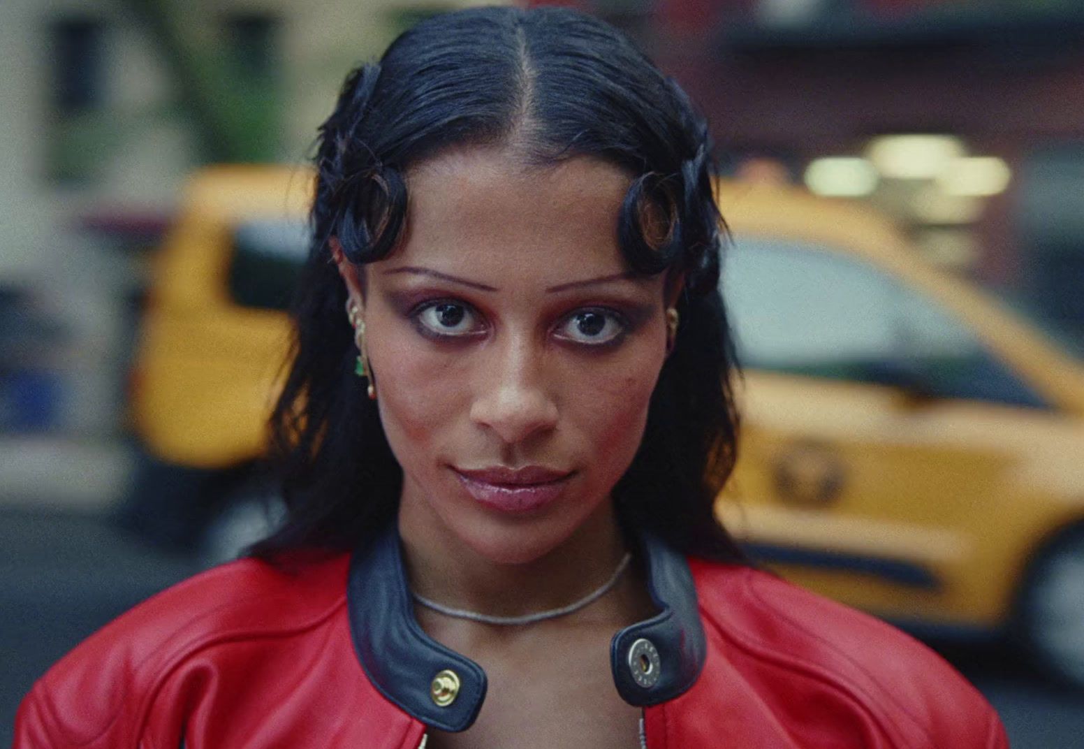 a woman in a red leather jacket looking at the camera