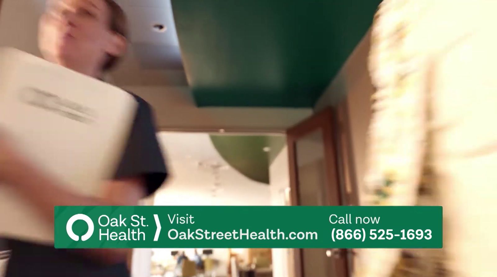 a man walking down a hallway holding a book