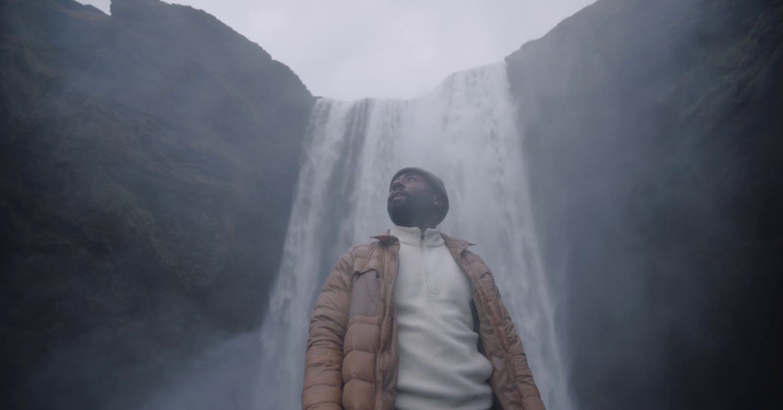 a man standing in front of a waterfall