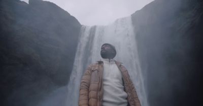 a man standing in front of a waterfall