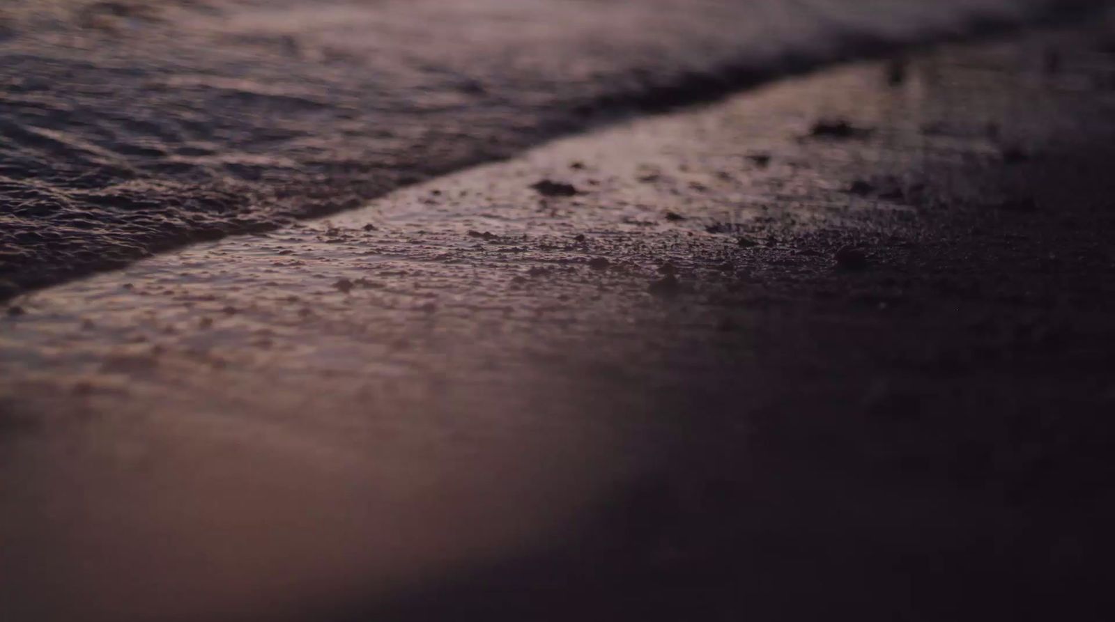 a close up of a wet beach with waves coming in