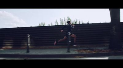 a man running down a sidewalk next to a fence