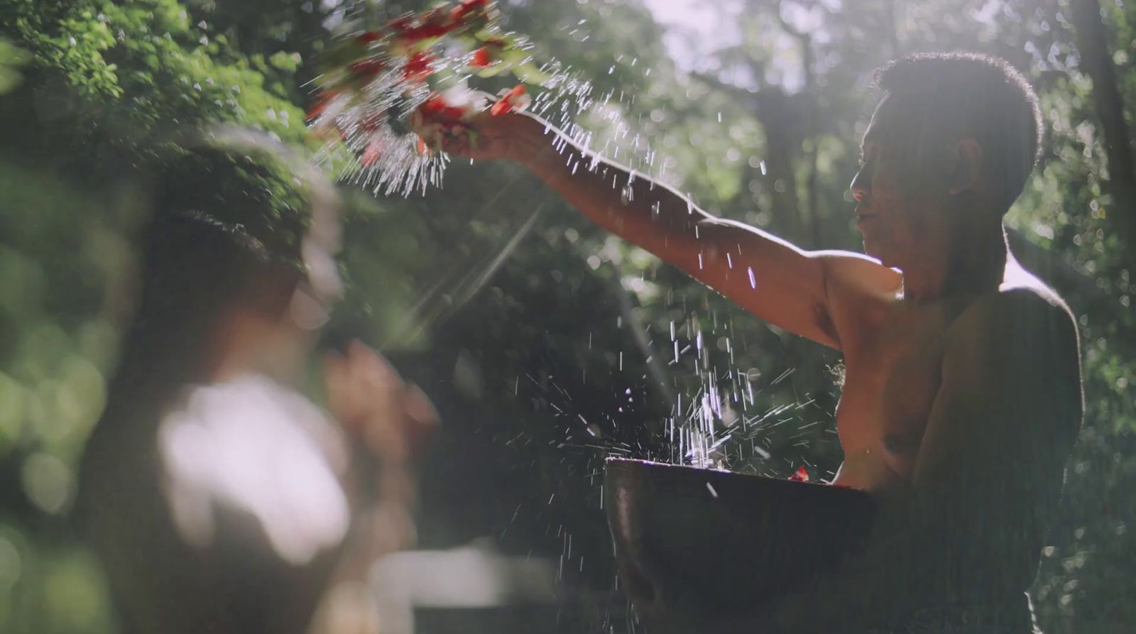 a man holding a bucket full of water in the woods