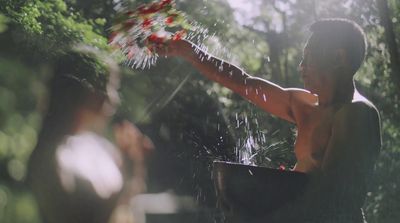 a man holding a bucket full of water in the woods