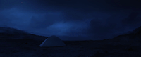 a tent in the middle of a field at night