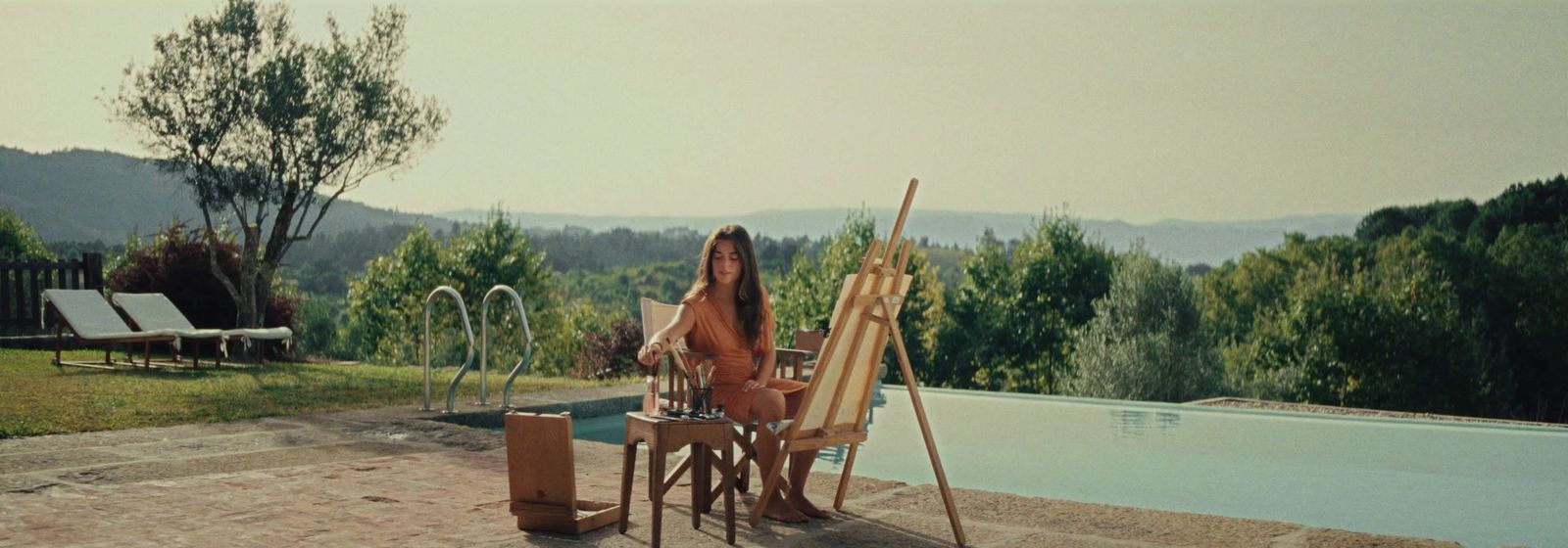 a woman sitting at a table next to a pool