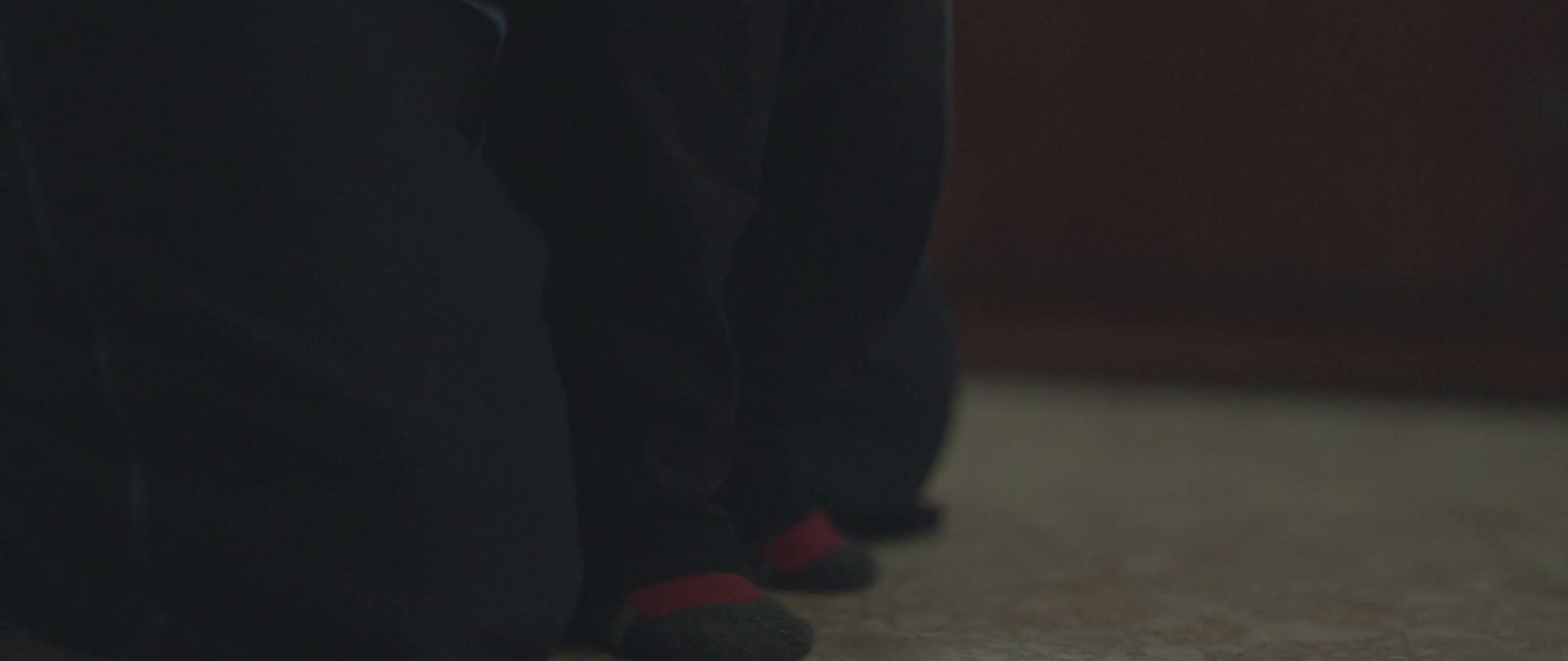 a close up of a person's feet wearing black pants and red socks