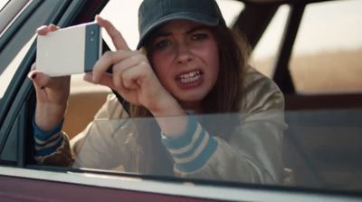 a woman holding up a camera while sitting in a car