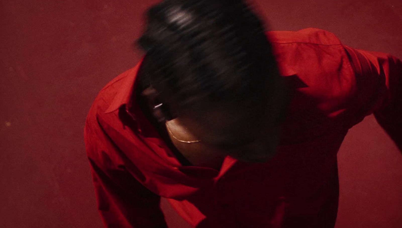 a woman in a red shirt looking down at her hair