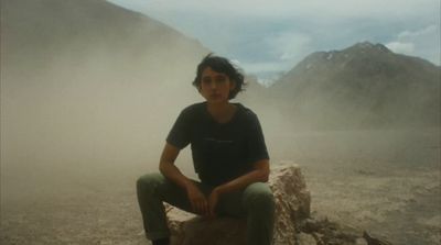 a woman sitting on a rock in the middle of a desert