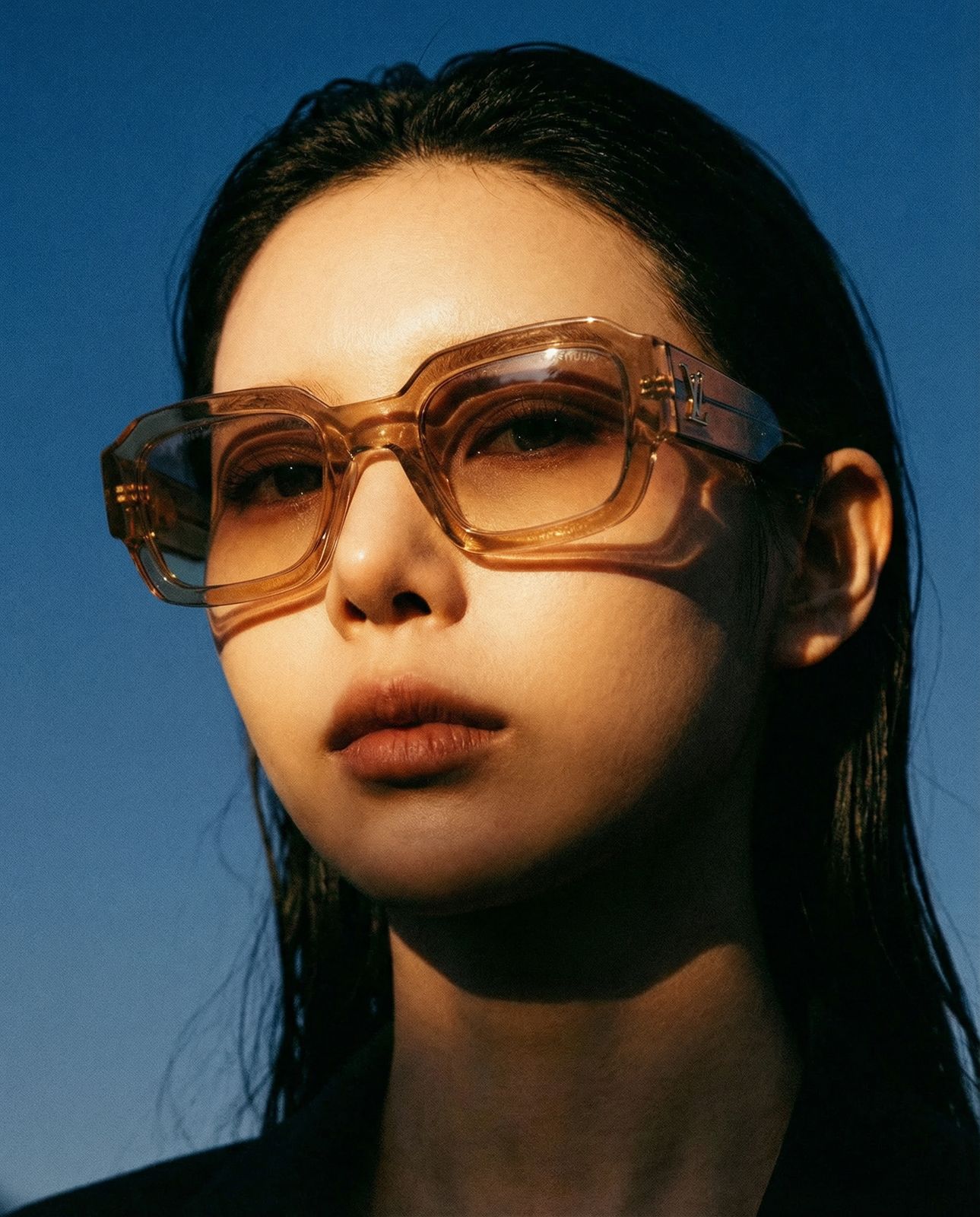 a woman wearing glasses with a blue sky in the background