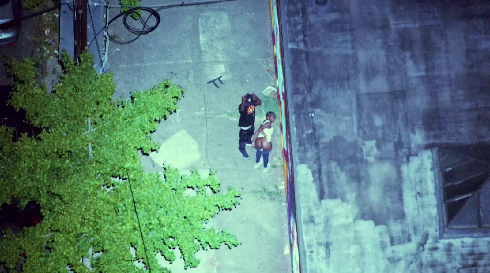 a couple of people walking down a street next to a tree