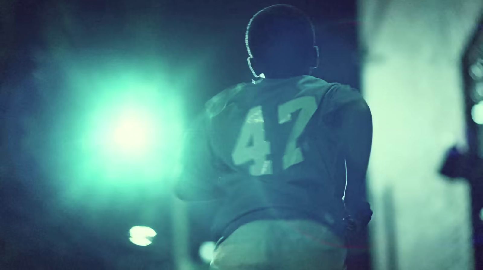 a man in a football uniform standing in front of a green light