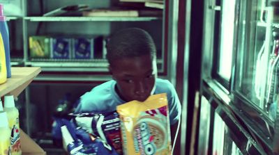 a young boy holding a bag of chips in front of a refrigerator