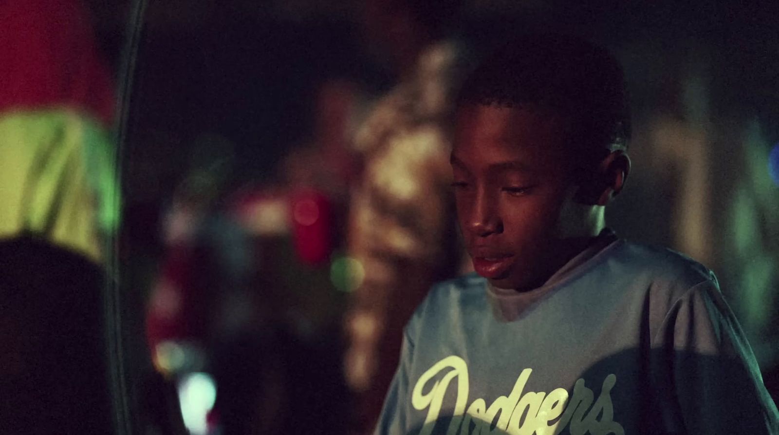 a young man standing in the dark with a cell phone to his ear