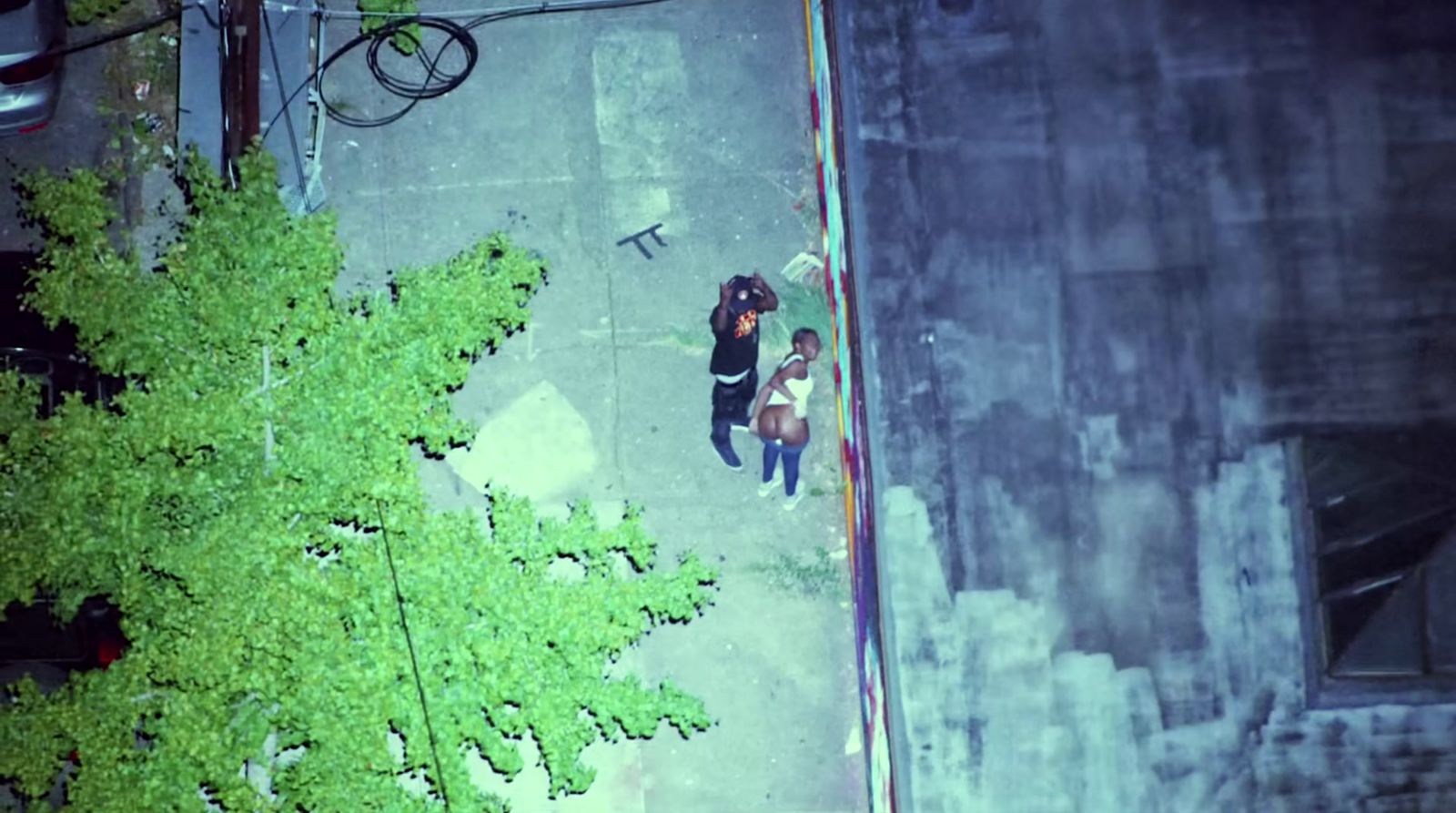 a couple of people walking down a street next to a tree