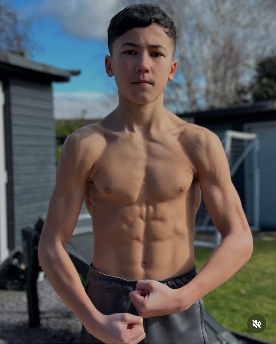 a shirtless young man standing in front of a house