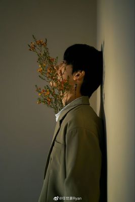 a man standing next to a wall holding a bunch of flowers