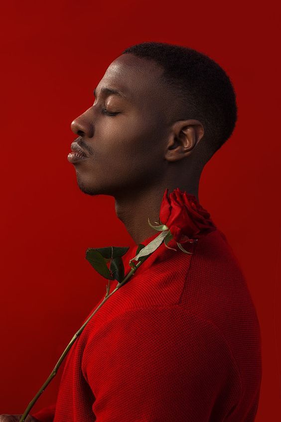 a man in a red shirt with a rose in his mouth