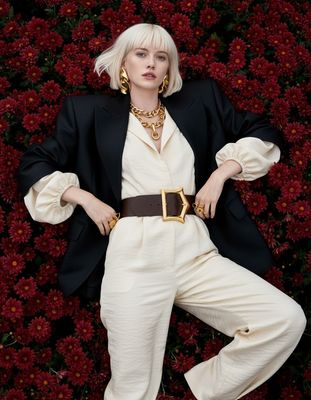 a woman with blonde hair wearing a black jacket and white pants