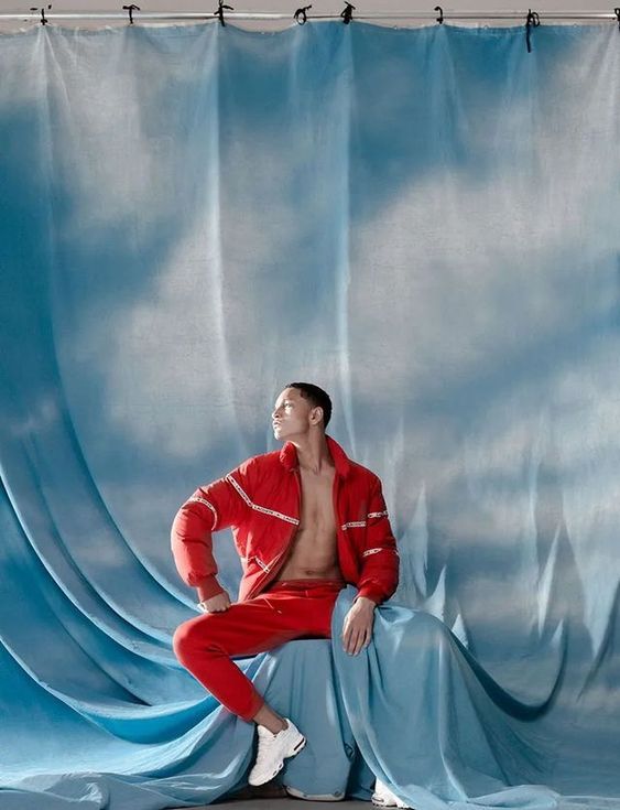 a man in a red suit sitting on a blue curtain